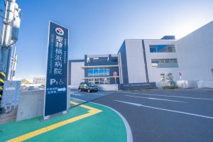 介護施設の建物外観。青空の下、白を基調とした現代的な建屋と駐車場が見える。